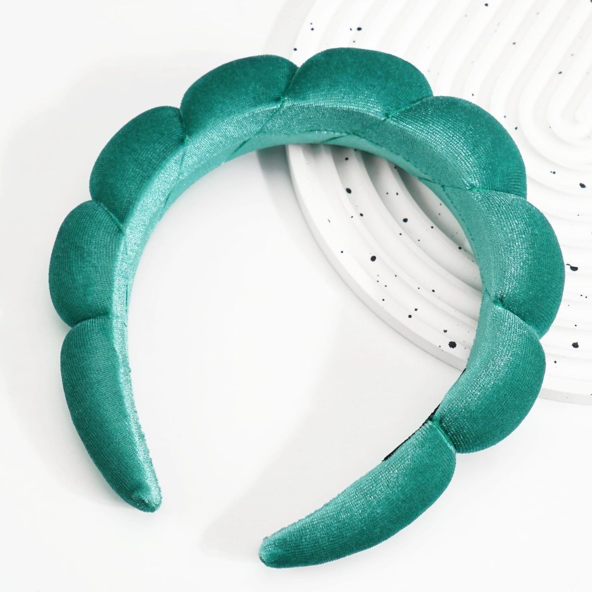 Bandeau Ayesha en velours vert sur table avec accessoires de beauté