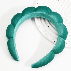 Bandeau Ayesha en velours vert sur table avec accessoires de beauté