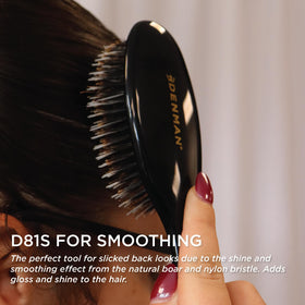 Brosse à cheveux Denman Cushion sur une coiffeuse avec accessoires