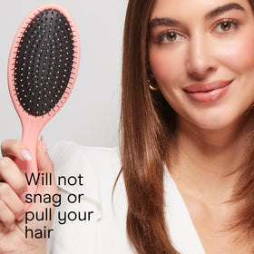 Brosse démêlante Conair en main avec cheveux noirs
