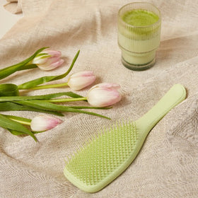 Brosse démêlante TANGLE TEEZER verte sur une surface blanche