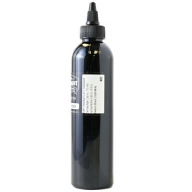 Flacon d'encre noire Nighthawk 8oz sur un bureau de tatouage
