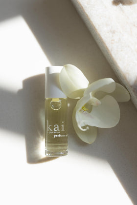 Flacon de parfum huile kai à la gardénia à côté d'autres produits de beauté