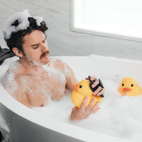 Gant de gommage MANSCAPED avec mise en scène de produits de bain