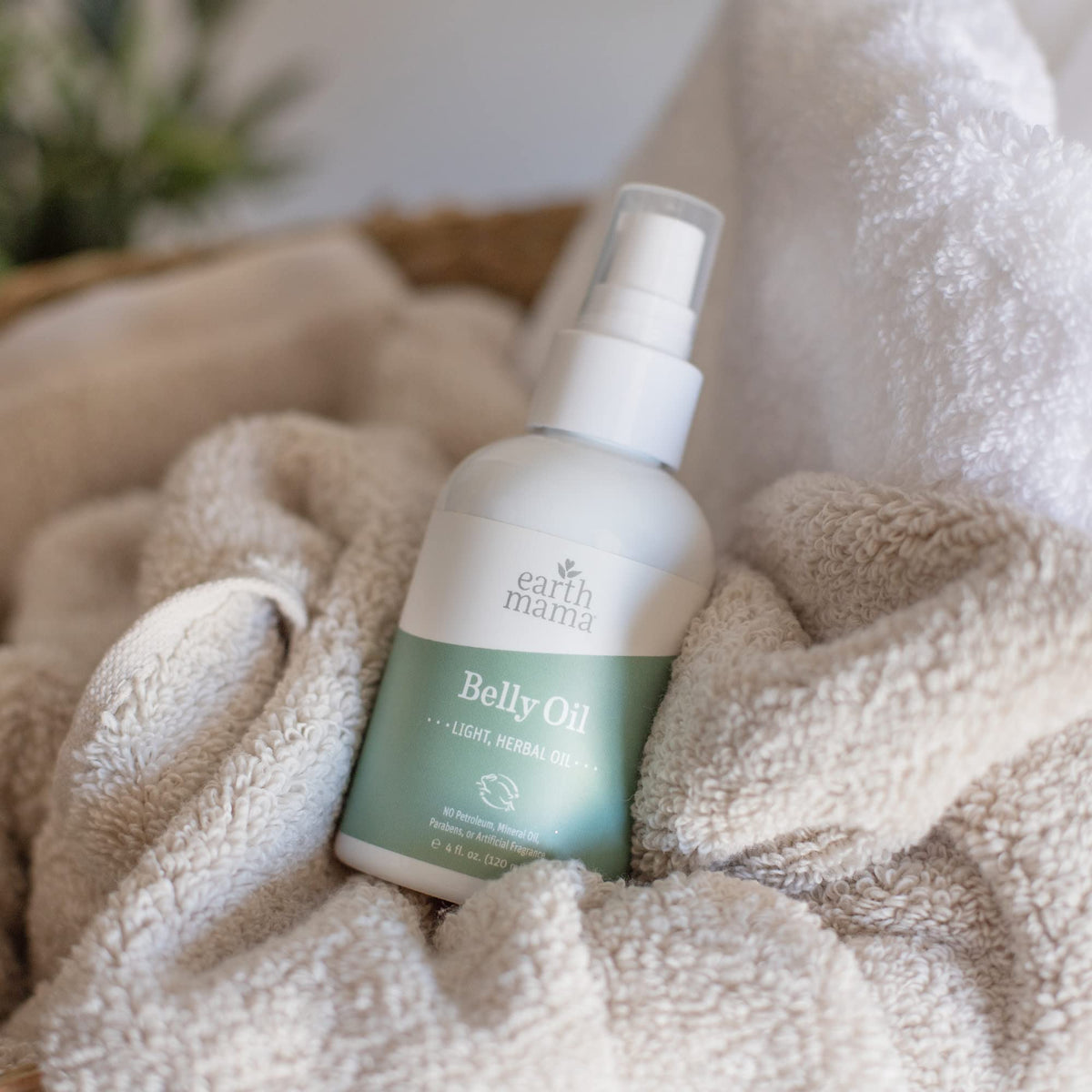 Huile de ventre Earth Mama avec une main appliquant le produit