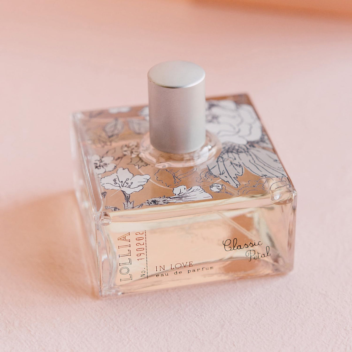 LOLLIA In Love Eau de Parfum 100 ml flacon sur fond de fleurs