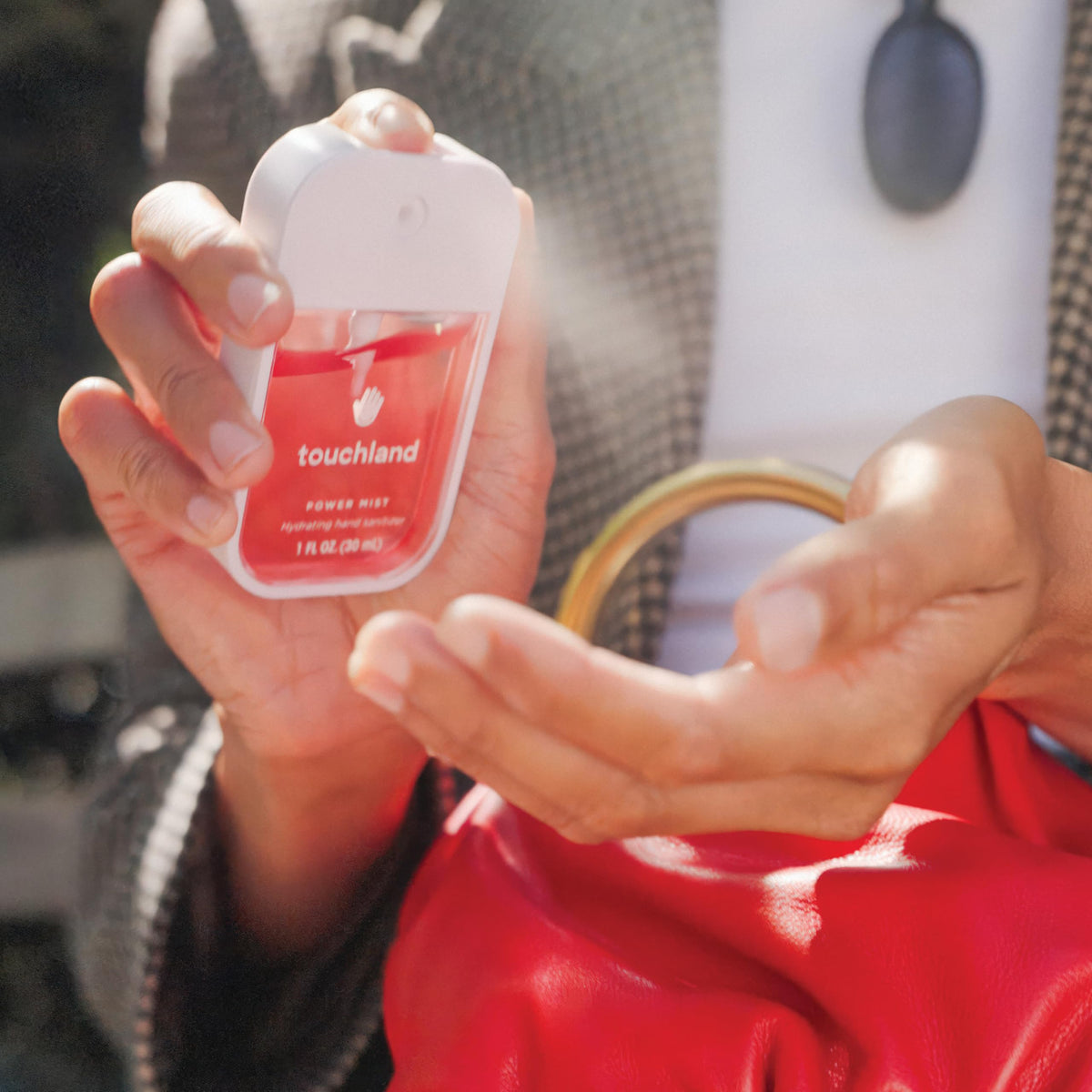 Mains utilisant le spray désinfectant Touchland en extérieur