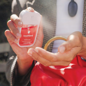 Mains utilisant le spray désinfectant Touchland en extérieur