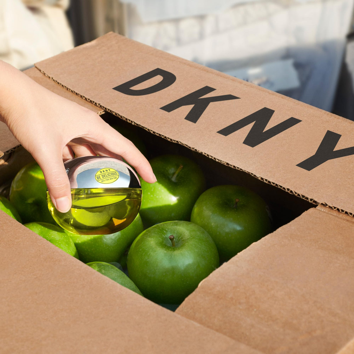 Parfum DKNY Be Delicious sur une table avec des pommes