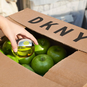 Parfum DKNY Be Delicious sur une table avec des pommes