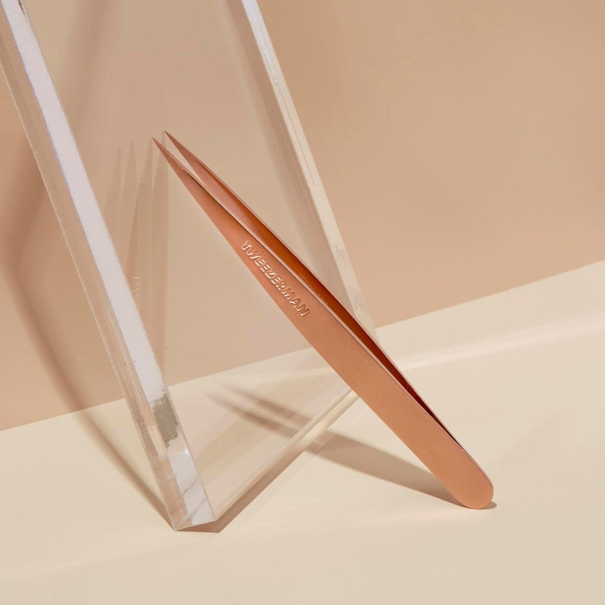 Pince à épiler Tweezerman sur un fond de maquillage