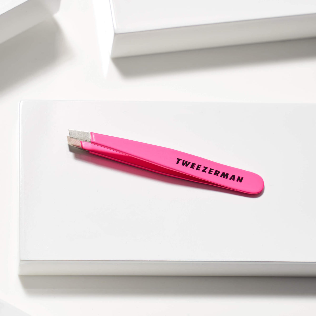Tweezerman Mini Pince à Épiler Slant rose néon en usage sur sourcils